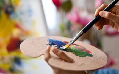 artist paintbrush and acrylics on paint palette links to adult programs webpage